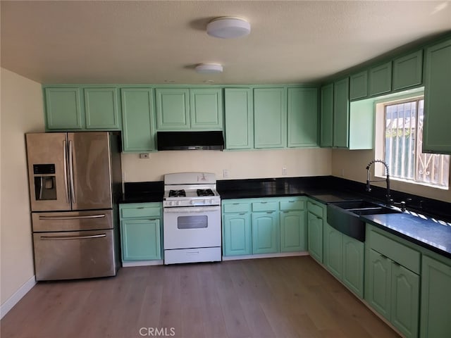 kitchen with under cabinet range hood, a sink, white gas range oven, stainless steel fridge with ice dispenser, and green cabinetry