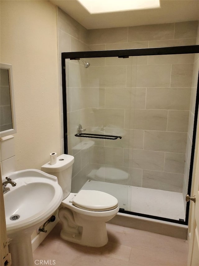 bathroom featuring toilet, a shower stall, and a sink