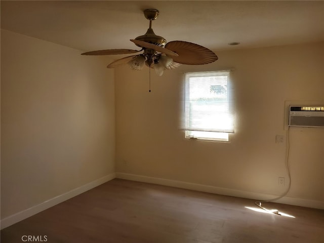 empty room featuring a wall unit AC, ceiling fan, baseboards, and wood finished floors