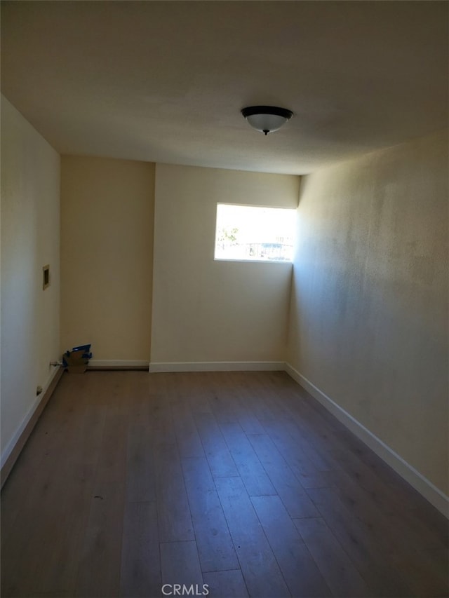 spare room featuring wood finished floors and baseboards