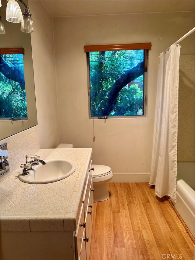 full bath featuring shower / tub combo, baseboards, toilet, wood finished floors, and vanity