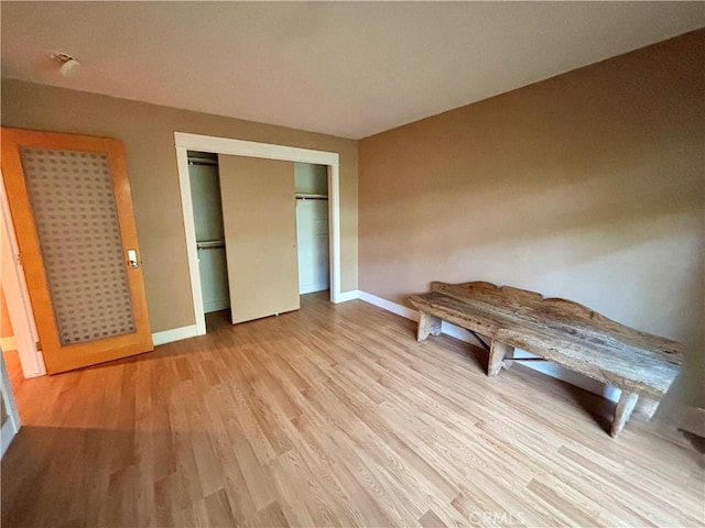 unfurnished bedroom featuring light wood-style floors, baseboards, and a closet