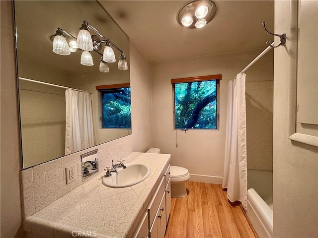 full bath featuring curtained shower, toilet, wood finished floors, vanity, and baseboards