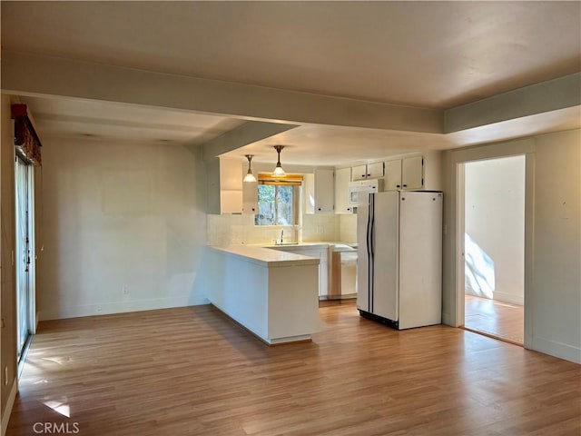 kitchen with white appliances, tasteful backsplash, light wood-style flooring, a peninsula, and light countertops