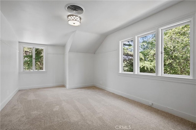 additional living space with carpet floors, a healthy amount of sunlight, visible vents, and lofted ceiling