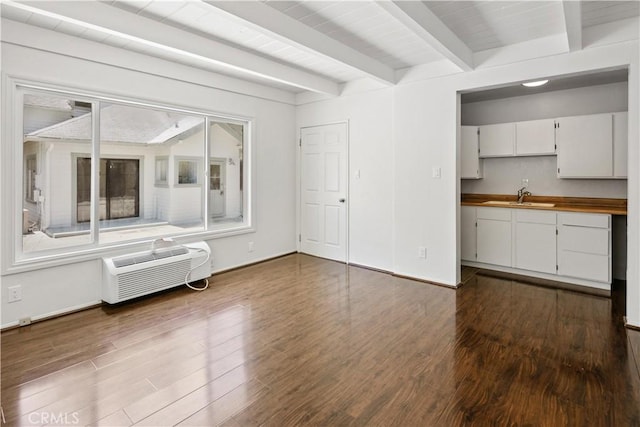 interior space featuring a sink, baseboards, a wall mounted AC, beam ceiling, and dark wood-style floors