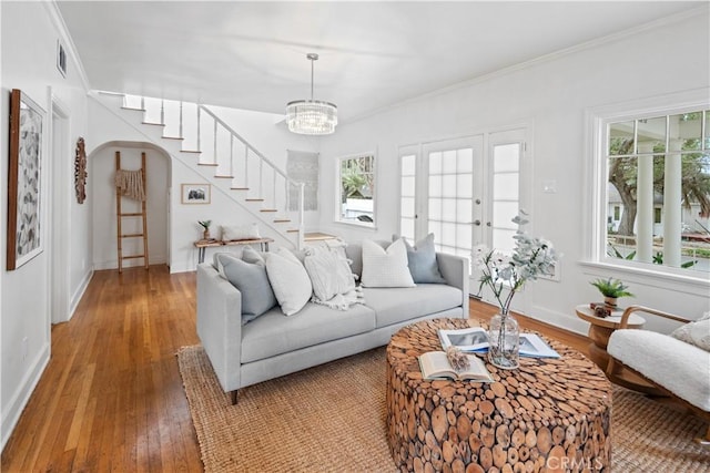 living area with arched walkways, a wealth of natural light, wood-type flooring, and visible vents