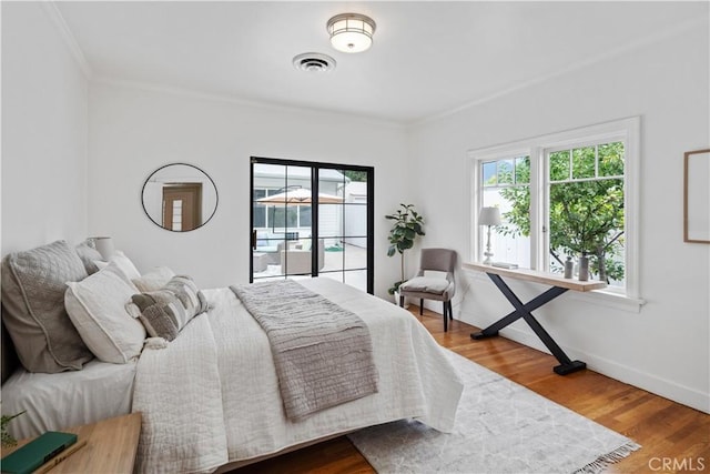 bedroom with visible vents, ornamental molding, wood finished floors, access to outside, and baseboards