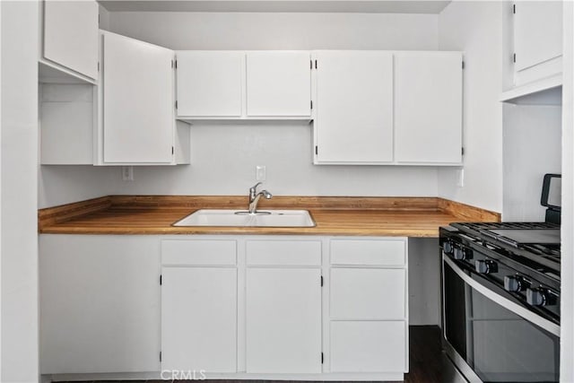 kitchen with gas range, white cabinets, and a sink