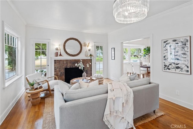 living area featuring baseboards, a fireplace, ornamental molding, and wood finished floors