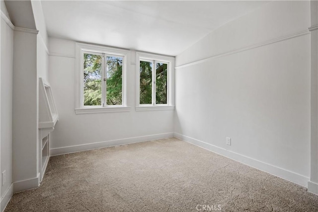 empty room with carpet floors, lofted ceiling, and baseboards