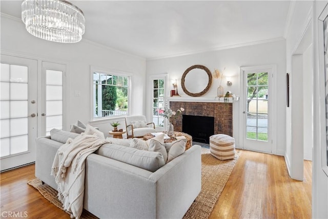 living room with a healthy amount of sunlight, light wood finished floors, and a brick fireplace