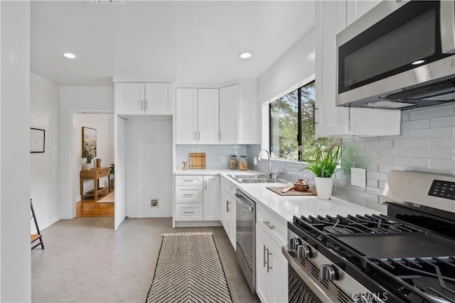 kitchen with white cabinetry, stainless steel appliances, a sink, and light countertops