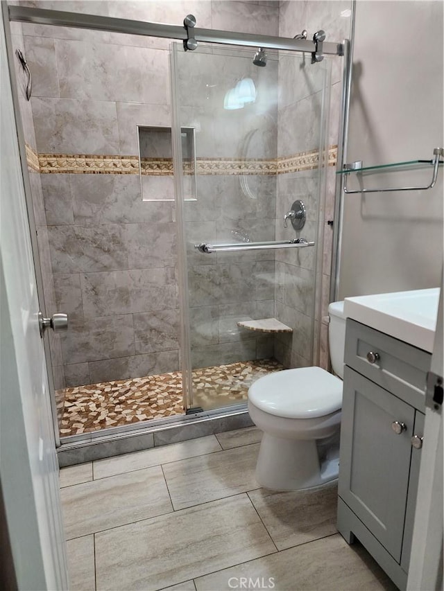 full bath with vanity, toilet, and a shower stall