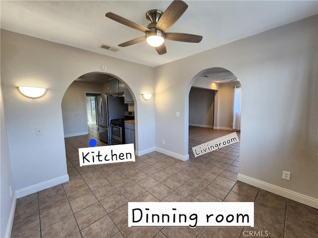 spare room with arched walkways, a ceiling fan, baseboards, visible vents, and tile patterned floors