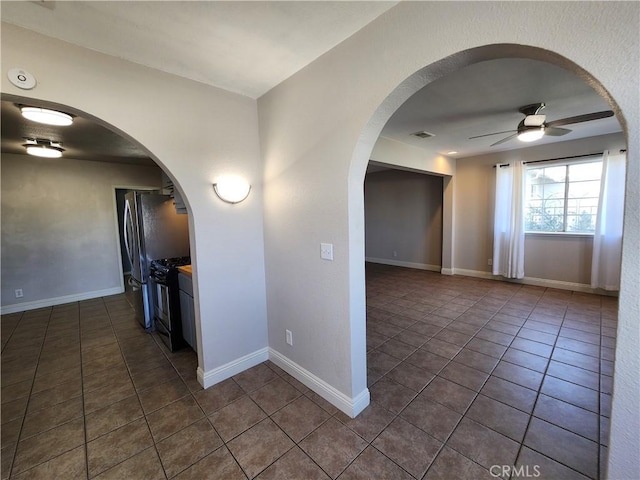 hall featuring baseboards, visible vents, arched walkways, and dark tile patterned flooring