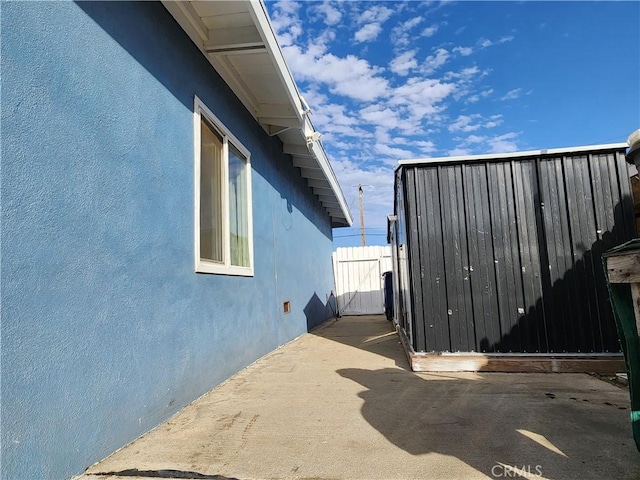 view of side of home featuring fence, a patio, and stucco siding