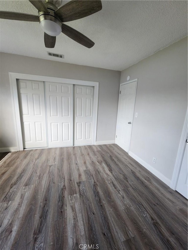 unfurnished bedroom featuring a closet, visible vents, baseboards, and wood finished floors