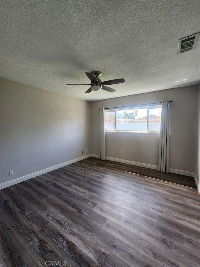 spare room with baseboards, visible vents, dark wood finished floors, ceiling fan, and a textured ceiling