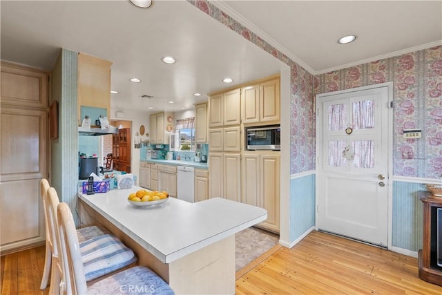 kitchen with a wainscoted wall, light wood finished floors, stainless steel microwave, dishwasher, and wallpapered walls