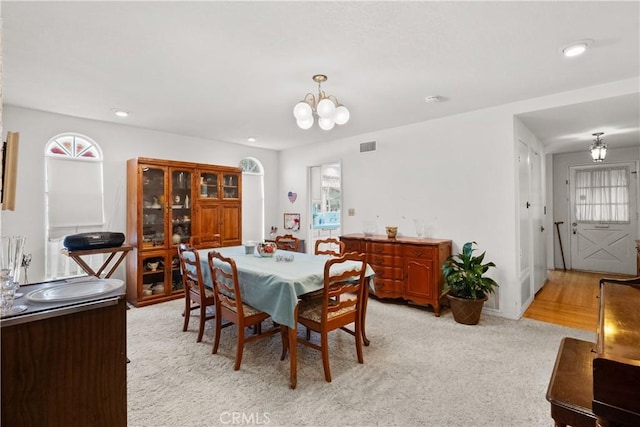 dining space with recessed lighting, light colored carpet, visible vents, and an inviting chandelier