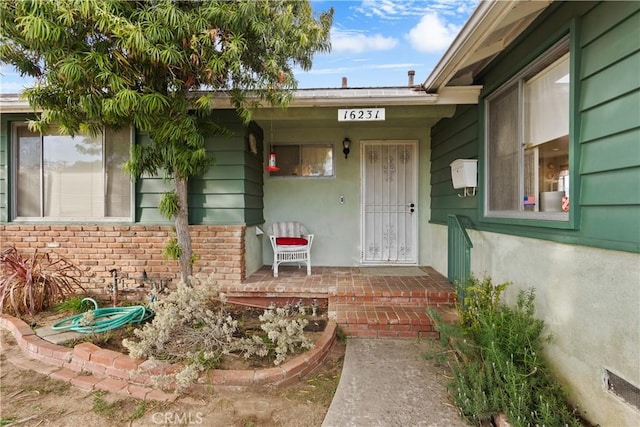 view of exterior entry featuring covered porch and brick siding