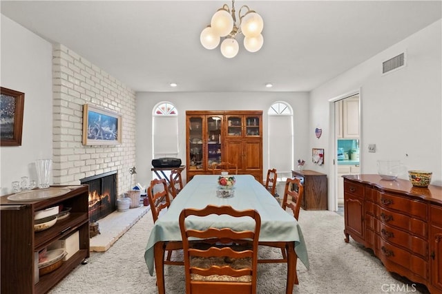 dining room with a chandelier, light carpet, a fireplace, and visible vents