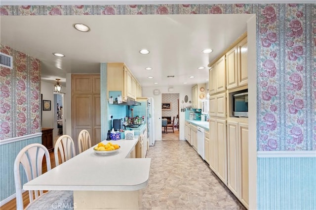 kitchen featuring white dishwasher, a wainscoted wall, a peninsula, light countertops, and built in microwave