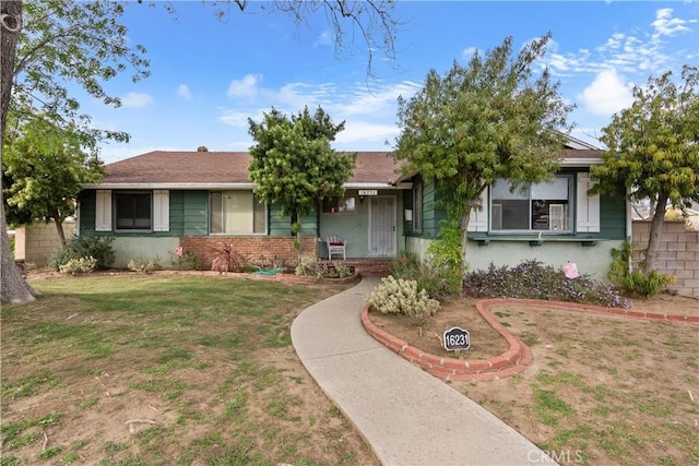 view of front of property featuring brick siding, fence, and a front yard