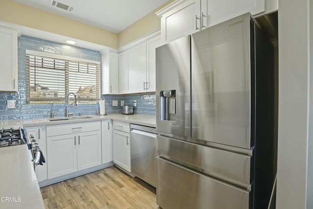 kitchen featuring visible vents, light countertops, decorative backsplash, stainless steel appliances, and a sink