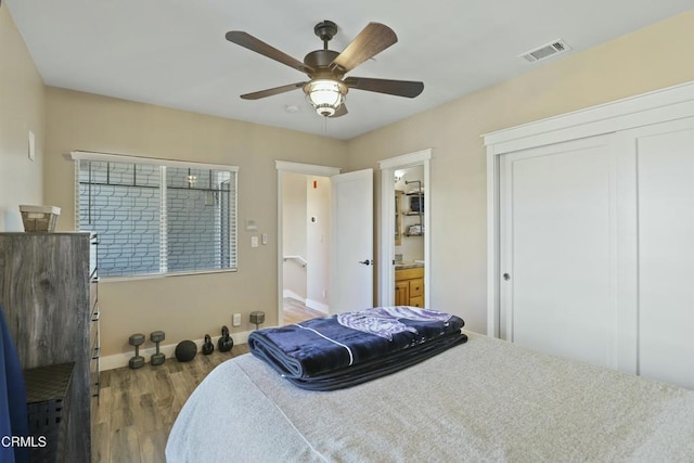 bedroom featuring visible vents, ensuite bathroom, a ceiling fan, wood finished floors, and baseboards