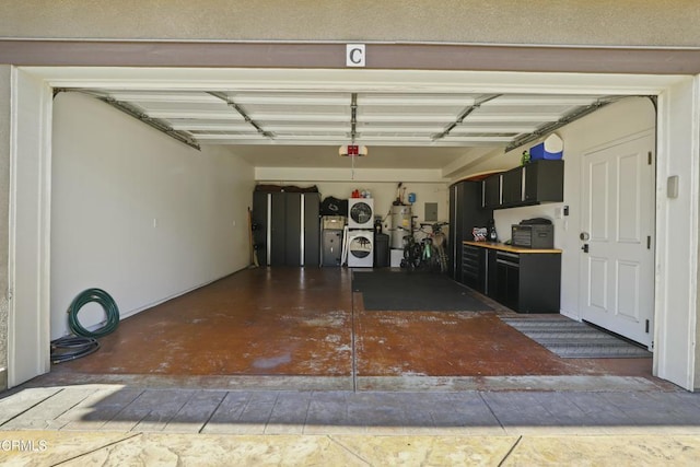 garage with washer and dryer, strapped water heater, electric panel, and a garage door opener