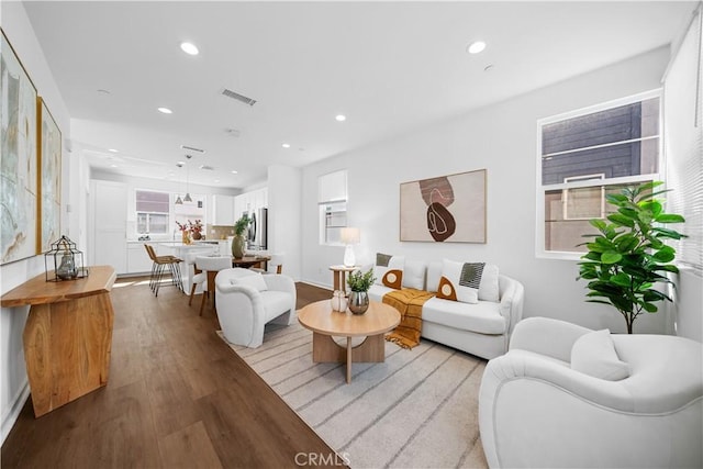 living area with wood finished floors, visible vents, and recessed lighting