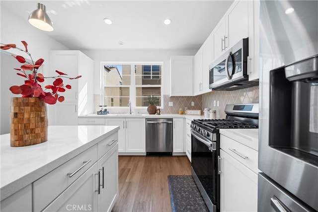 kitchen featuring light countertops, appliances with stainless steel finishes, a sink, and decorative backsplash