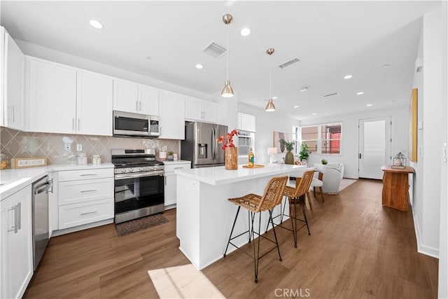 kitchen with white cabinets, visible vents, stainless steel appliances, and a breakfast bar area