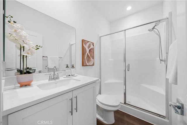 full bathroom featuring recessed lighting, toilet, a shower stall, vanity, and wood finished floors