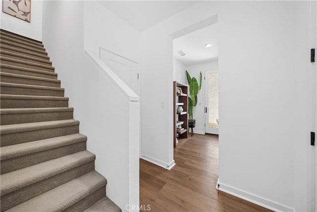 stairs with wood finished floors, visible vents, and baseboards