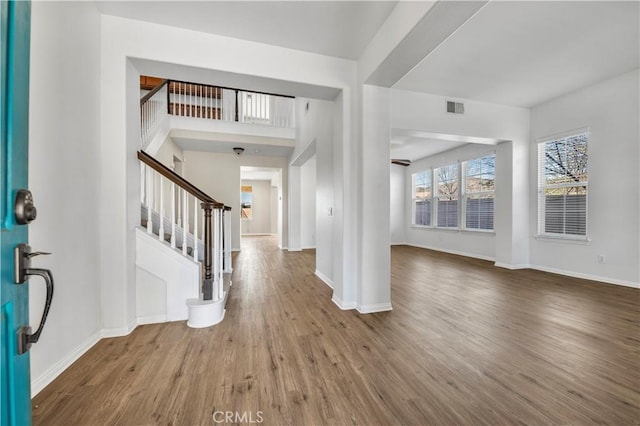 entrance foyer featuring stairs, visible vents, baseboards, and wood finished floors