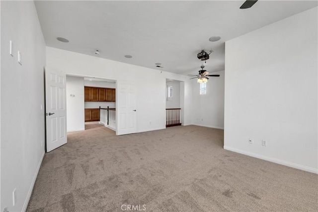 unfurnished living room featuring light carpet, baseboards, and a ceiling fan