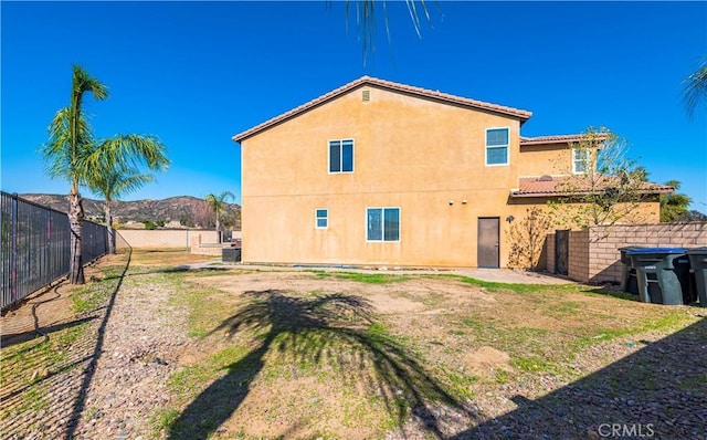 rear view of property featuring a fenced backyard, a yard, central AC unit, and stucco siding