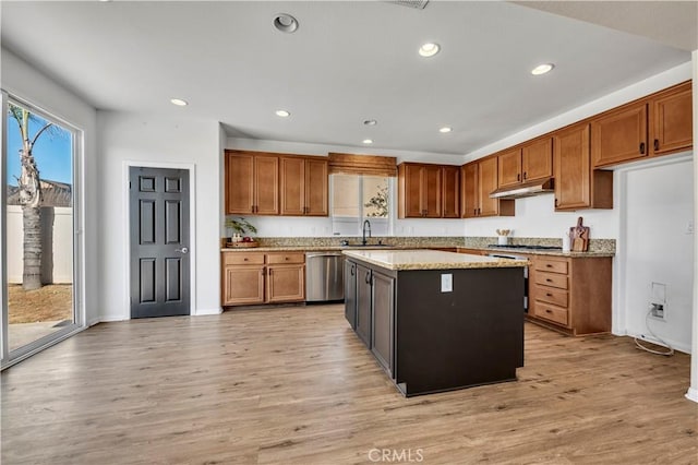 kitchen featuring stainless steel appliances, brown cabinetry, light wood-style flooring, and under cabinet range hood