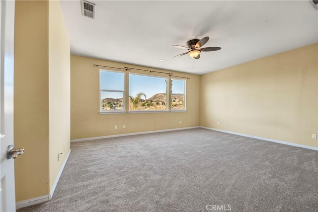 empty room featuring carpet floors, baseboards, visible vents, and a ceiling fan