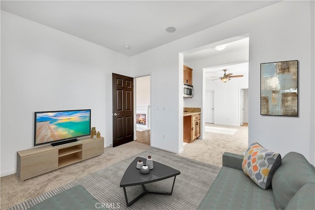 living room featuring a ceiling fan, light carpet, and baseboards