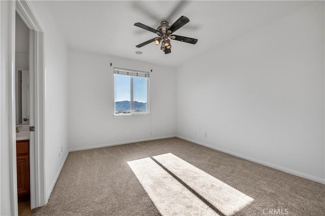 empty room with carpet floors, a ceiling fan, and baseboards