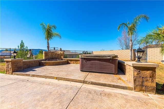 view of patio featuring a hot tub and fence