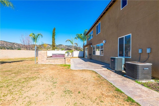 view of yard with a patio area, a fenced backyard, a mountain view, and central AC