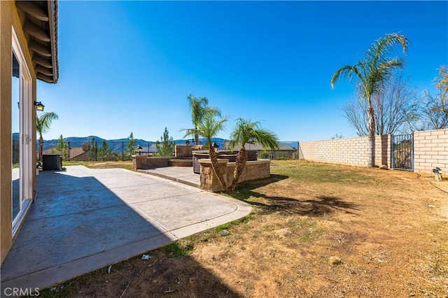 view of yard with central AC unit, a mountain view, fence, a gate, and a patio area