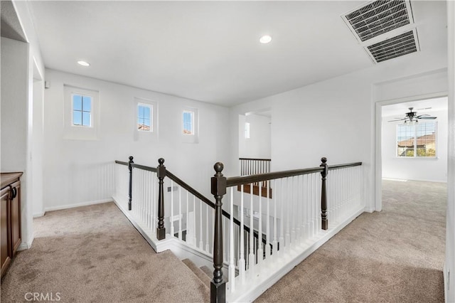 hall featuring plenty of natural light, visible vents, carpet flooring, and an upstairs landing