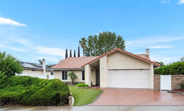 view of front facade featuring a tiled roof, decorative driveway, an attached garage, and stucco siding