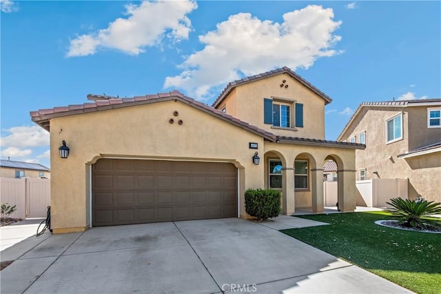 mediterranean / spanish home with driveway, fence, and stucco siding